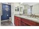 Modern bathroom with dual sinks, granite countertops, red cabinetry, and stylish decor on a blue wall at 1072 3Rd Nw Ave, Carmel, IN 46032