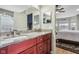 Elegant bathroom featuring double sinks with granite countertop and cherry cabinetry, plus a view to the bedroom at 1072 3Rd Nw Ave, Carmel, IN 46032
