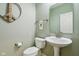 Charming powder room features a pedestal sink, toilet, decorative peace sign art, and soothing green walls at 1072 3Rd Nw Ave, Carmel, IN 46032