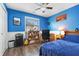 Vibrant blue bedroom featuring hardwood floors, a ceiling fan, and a well-lit desk area at 12205 Whitebark Dr, Indianapolis, IN 46236