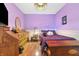 Cozy bedroom with hardwood floors, dresser, white iron bed frame, and purple color scheme at 12205 Whitebark Dr, Indianapolis, IN 46236