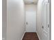 Neutral hallway with hardwood floors leading to a white door and trim at 12863 Tradd St # 1D, Carmel, IN 46032