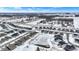 Winter aerial showcasing a residential community with modern homes and a partially frozen pond covered in snow, under a bright sky at 5461 Oak Knoll Dr, Whitestown, IN 46075