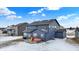 Backyard view of a blue two-story home with patio, covered in snow, showcasing a simple outdoor space under a bright winter sky at 5461 Oak Knoll Dr, Whitestown, IN 46075