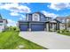 Stylish two-story home with a three car garage, blue siding, stone accents, and manicured green lawn at 5461 Oak Knoll Dr, Whitestown, IN 46075