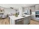 Well-lit kitchen with island, stainless steel appliances, gray cabinets, and open view to the living room with fireplace at 5461 Oak Knoll Dr, Whitestown, IN 46075
