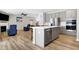 Open concept kitchen with stainless steel appliances, island with bar seating, and hardwood floors at 5461 Oak Knoll Dr, Whitestown, IN 46075