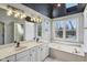 This bathroom boasts double sinks, a soaking tub, and stylish lighting fixtures at 7238 River Birch Ln, Indianapolis, IN 46236