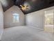 A vaulted ceiling bedroom with neutral walls and carpet, ceiling fan, and a view to the bathroom at 7238 River Birch Ln, Indianapolis, IN 46236