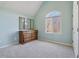 A serene bedroom with a vaulted ceiling, large arched window, and wooden dresser with mirror at 7238 River Birch Ln, Indianapolis, IN 46236
