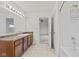Well-lit bathroom showcasing a vanity with cabinets, a tub with shower, and doorway leading into a bedroom at 8547 S Tibbs Ave, Indianapolis, IN 46217