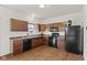 Well-lit kitchen boasts wooden cabinets, sleek black appliances, and laminate floors at 8547 S Tibbs Ave, Indianapolis, IN 46217