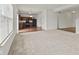 Open-concept living room with carpeted area adjoining a kitchen with rich wood cabinets and modern appliances at 8547 S Tibbs Ave, Indianapolis, IN 46217