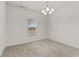 Bright, carpeted room with a modern chandelier and a window providing natural light at 8547 S Tibbs Ave, Indianapolis, IN 46217