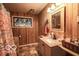 Bathroom featuring wood paneling, a decorative mirror, granite countertop, sink and framed stained glass window at 9464 N State Rd 135, Morgantown, IN 46160
