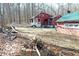 Exterior shot showcasing the red house and shed, along with a brick firepit, set against a backdrop of woods at 9464 N State Rd 135, Morgantown, IN 46160
