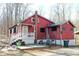 Quaint red home featuring a cozy front porch and a small back deck with a peaceful wooded backdrop at 9464 N State Rd 135, Morgantown, IN 46160