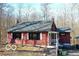 Charming red home with a brick chimney and gray roof nestled amongst mature trees at 9464 N State Rd 135, Morgantown, IN 46160