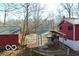 A view of a red house with a green roof shed and a carport in a wooded landscape at 9464 N State Rd 135, Morgantown, IN 46160