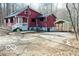 The red house and an adjacent carport are featured in a natural setting with a gravel driveway at 9464 N State Rd 135, Morgantown, IN 46160