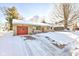 Ranch style home with a snow-covered front yard, stone siding, and a driveway leading to a red garage door at 115 N Spring St, Greenfield, IN 46140