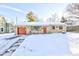 Charming single-story home with a red garage door, stone facade, and a snow-covered front yard at 115 N Spring St, Greenfield, IN 46140