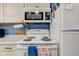 Close-up of a modern white stove and microwave with marble countertops and blue accents at 115 N Spring St, Greenfield, IN 46140