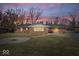 Twilight view of a brick home's backyard with fire pit and yard at 1313 Oakwood Trl, Indianapolis, IN 46260