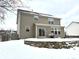 Rear exterior featuring a stone retaining wall, a patio with grill, and snow-covered yard at 14596 Toponas Pl, Fishers, IN 46040