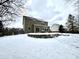 Backyard view of a house with a retaining wall and a snow-covered yard at 14596 Toponas Pl, Fishers, IN 46040