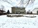 Exterior backyard view featuring a stone retaining wall, patio with grill, and snow-covered lawn at 14596 Toponas Pl, Fishers, IN 46040