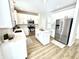 Well-lit kitchen with white cabinetry, stainless steel refrigerator, and a central island with a white countertop at 14596 Toponas Pl, Fishers, IN 46040