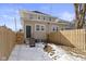 A fenced backyard with a combination of snow and exposed dirt, and a view of the home's back entrance and upper stories at 17 Parkview Ave, Indianapolis, IN 46201