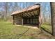 Open barn with a metal roof offers shelter and storage space for outdoor equipment and is surrounded by a wooded area at 1828 W 750 S, Trafalgar, IN 46181