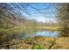 A calm pond reflects the sky, surrounded by trees, foliage, and fresh spring sprouts in a peaceful setting at 1828 W 750 S, Trafalgar, IN 46181