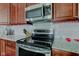A kitchen with stainless steel appliances, granite countertops, wood cabinets, and tile backsplash at 2180 Quarter Path Rd, Cicero, IN 46034
