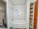Bathroom featuring a bathtub, shower with white marble-style wall, shelving, and water heater at 3049 Foltz St, Indianapolis, IN 46241