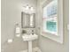 Cozy bathroom with pedestal sink, framed mirror, and natural light from the window at 4029 Broadway St, Indianapolis, IN 46205