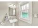 Bathroom featuring a pedestal sink, mirror, and window at 4029 Broadway St, Indianapolis, IN 46205