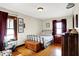 Comfortable bedroom with wood floors, metal-framed bed, and decorative art; bright windows fill the space at 4029 Broadway St, Indianapolis, IN 46205