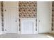 Bedroom with floral wallpaper accent, white fireplace, and two white doors with trim at 5752 River Rd, Waldron, IN 46182