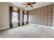 Bedroom with decorative wallpaper accent wall, two windows, and neutral carpet at 5752 River Rd, Waldron, IN 46182