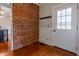 Inviting entryway showcasing a exposed brick wall, wood floors, and a white front door at 5752 River Rd, Waldron, IN 46182