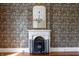 Classic fireplace with white mantel and decorative wallpaper, highlighted by a vintage mirror at 5752 River Rd, Waldron, IN 46182