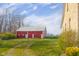 Large red barn with white trim is set amidst a vibrant green lawn under a clear blue sky at 5752 River Rd, Waldron, IN 46182