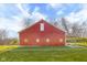 Spacious red outbuilding boasts ample windows, nestled within a verdant landscape at 5752 River Rd, Waldron, IN 46182