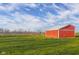 Brightly painted outbuilding surrounded by a lush green lawn, under a blue sky with wispy clouds at 5752 River Rd, Waldron, IN 46182