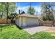 View of a detached, one-car garage with gravel parking area and fenced yard on a sunny day at 828 Woodruff Place Middle Dr, Indianapolis, IN 46201