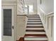 Traditional staircase featuring white wainscoting, dark wood treads, and a glass paneled door at 828 Woodruff Place Middle Dr, Indianapolis, IN 46201