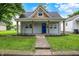 Charming home featuring a cozy front porch, blue door, and a well-maintained lawn and landscaped garden at 952 N Concord St, Indianapolis, IN 46222